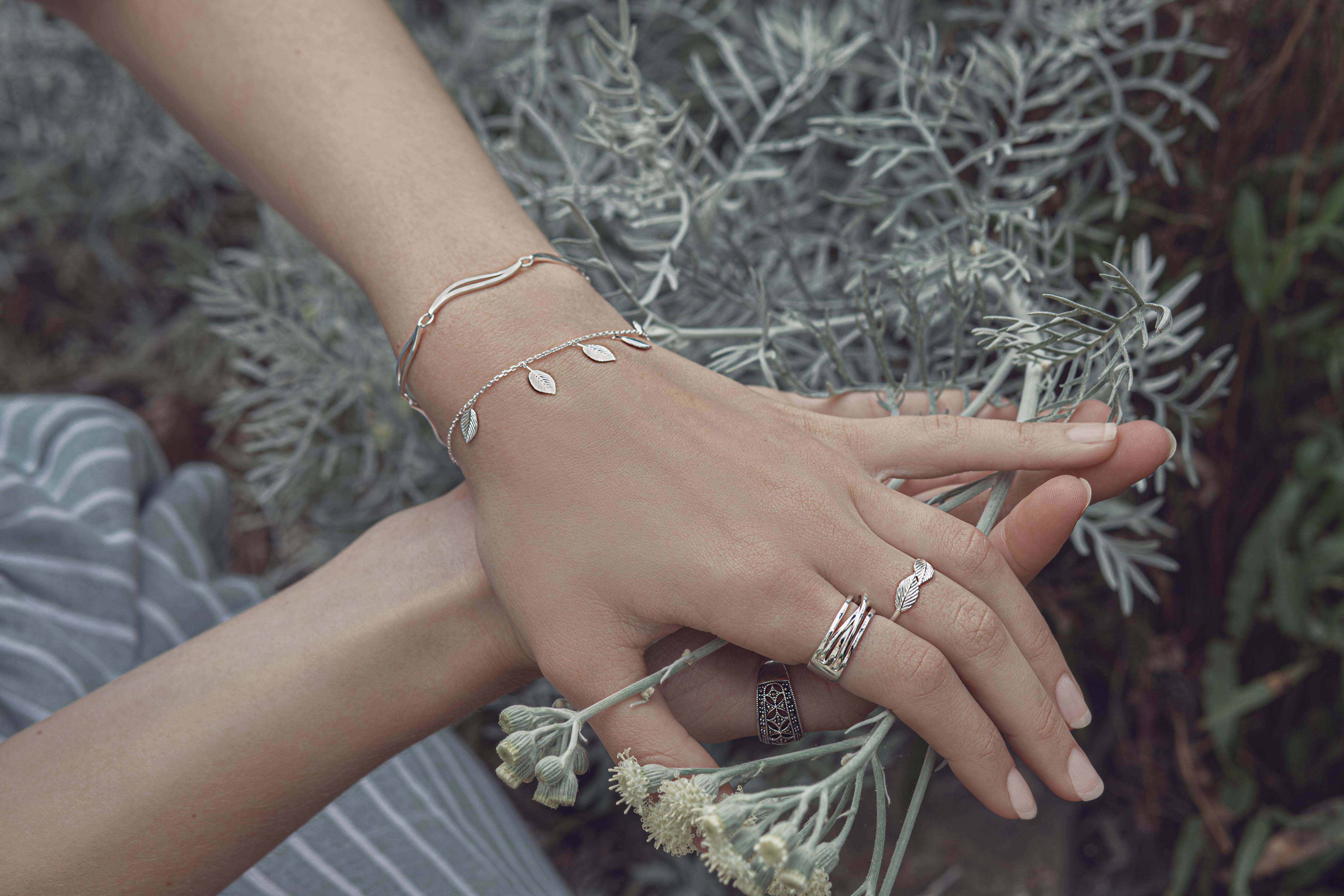 A ladies hands showcasing beautiful sterling silver designer bracelets and rings.