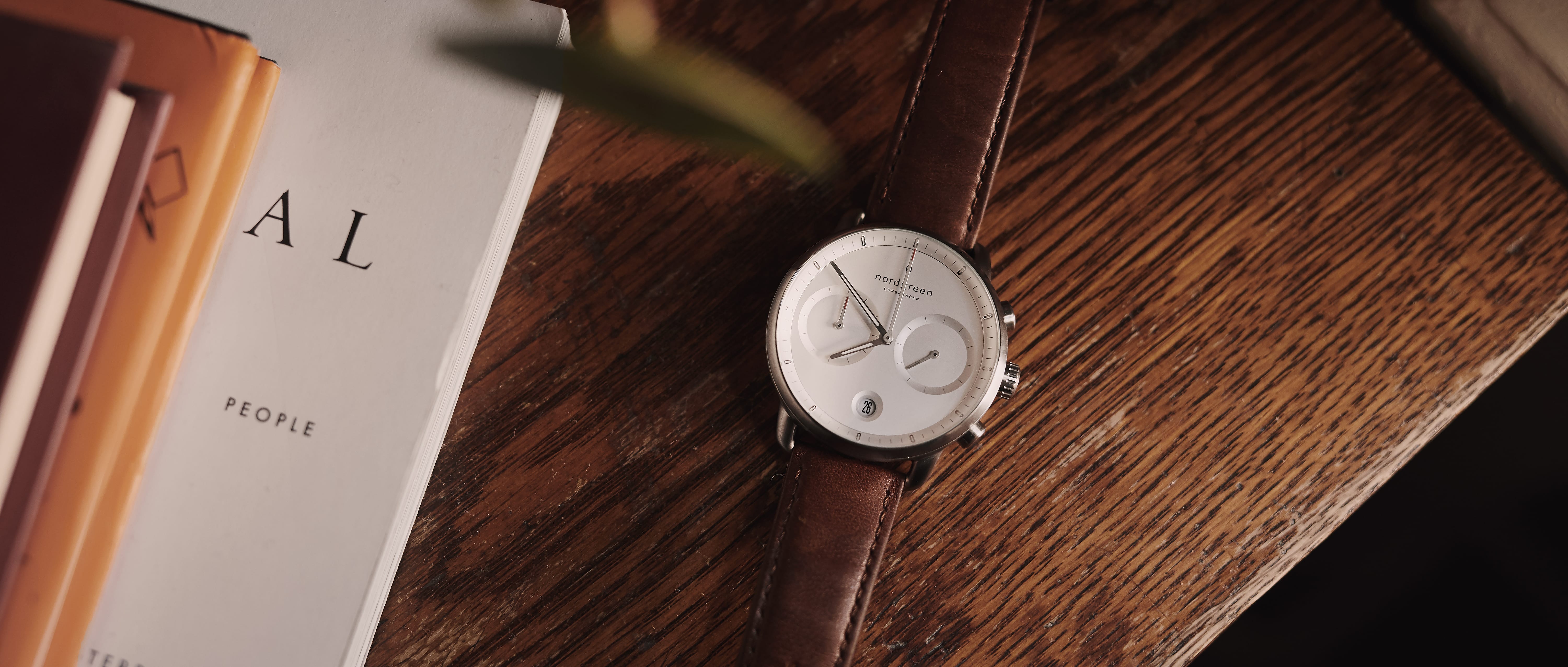 Nordgreen Watch with Brown Leather Strap & White Interface Laid on a Wooden Surface
