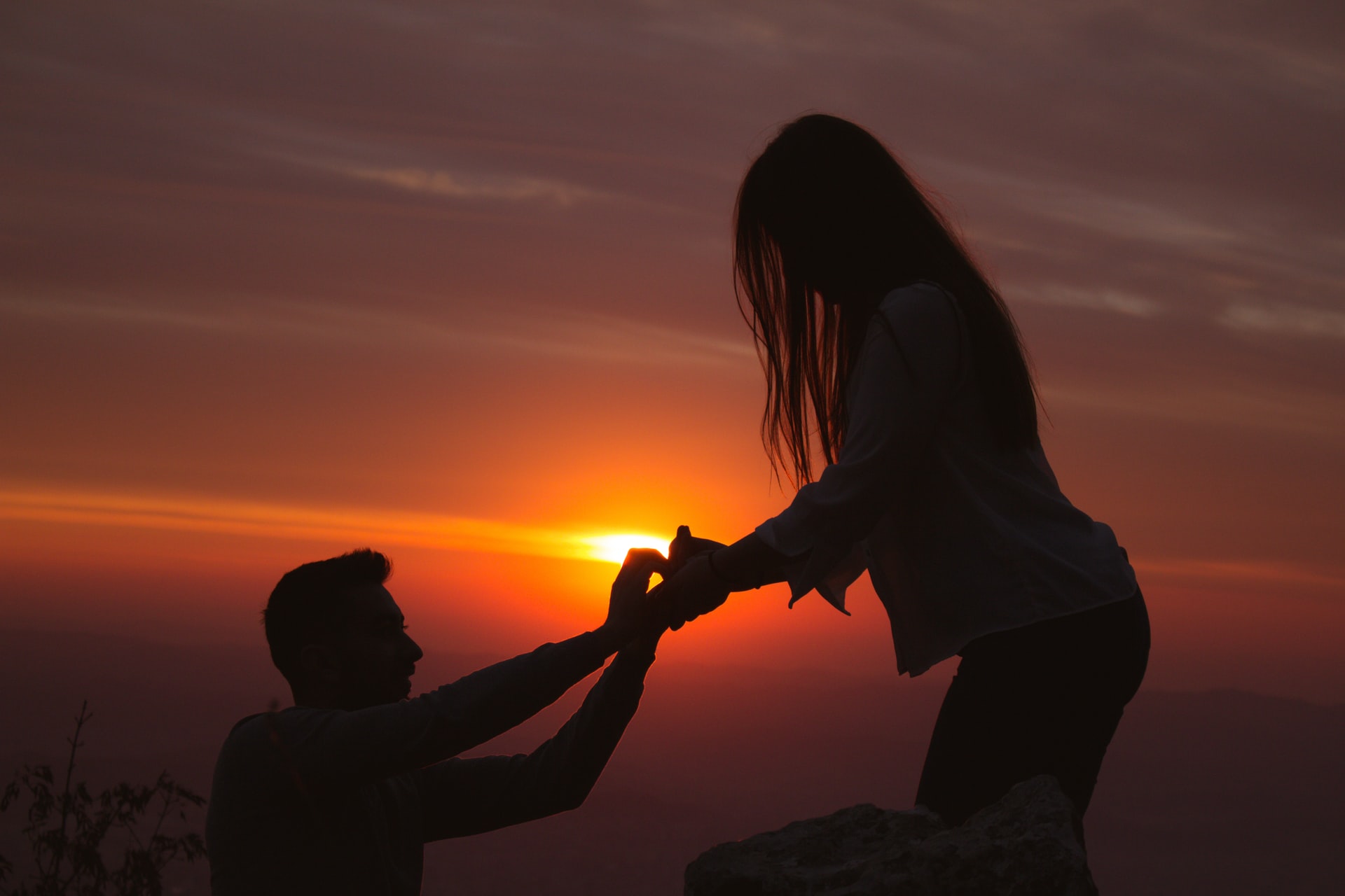 Silhouette photography of man proposing to girlfriend at sunset