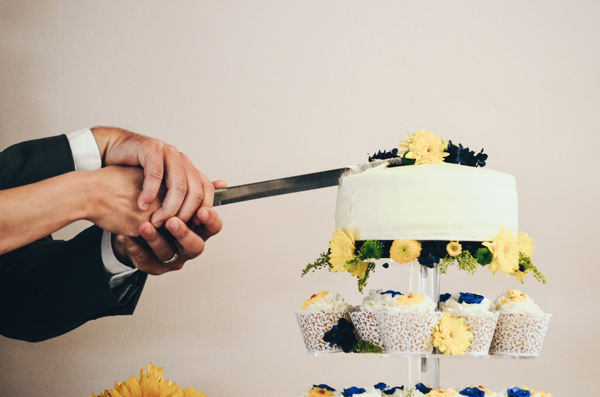 Couple holding hands as they slice wedding cake