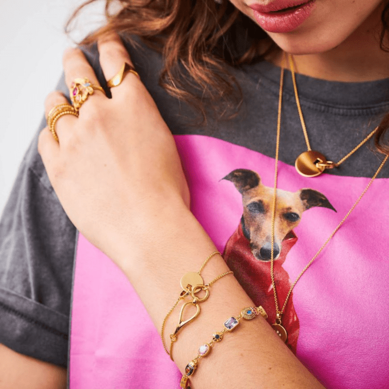 Ethical jewellery from Thomas Sabo- a model wearing necklaces, bracelets and rings on top of a pink dog top